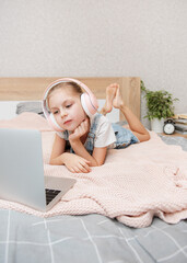 Wall Mural - Little girl learning online with laptop computer at bedroom.