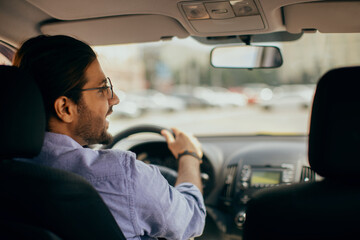 Wall Mural - Back view of middle-eastern guy driving auto