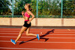 © nazarovsergey - Side view beautiful young woman exercise jogging and running on athletic track on stadium