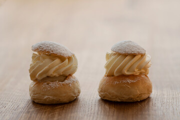 Two pieces of traditional Swedish pastry, the semla, on wooden table. Two-layer bun, stuffed with almond paste under a cover of thick layered whipped cream. Photo made in Sweden.