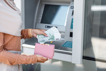 Wall Mural - Millennial unrecognizable arab muslim female in hijab withdraw money, put euro in wallet near ATM