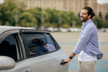 Wall Mural - Cheerful middle-eastern man in casual getting in taxi