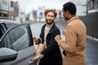 © rh2010 - Two men flirting or having a close conversation while opening car door on the street. Concept of homosexual relations or close male friendship. Caucasian and hispanic man wearing coats