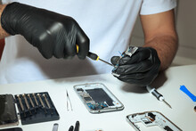 Technician Repairing Broken Smartphone At White Table, Closeup