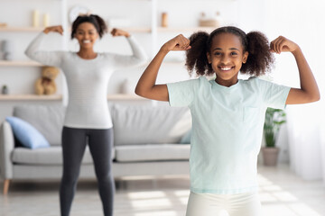 Wall Mural - Cheeful teen black girl showing her muscles