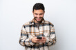 © luismolinero - Young Brazilian man isolated on white background sending a message with the mobile
