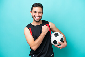 Wall Mural - Young football player Brazilian man isolated on blue background celebrating a victory