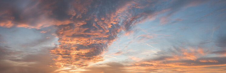 Wall Mural - dreamy sunset panorama with pink and orange lighted clouds, blue sky