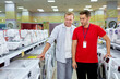 © alfa27 - male customer choosing washing machine in shop. difficult decision. Various choice. handsome nice consultant help with choice, talking, discussing which option is best. consumerism concept