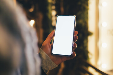 Woman's hand holding smartphone with blank screen outdoors