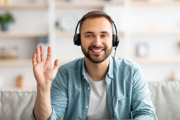 Poster - Young guy wearing headphones, waving hand at webcam, greeting friend or colleague online, having video call, screen view