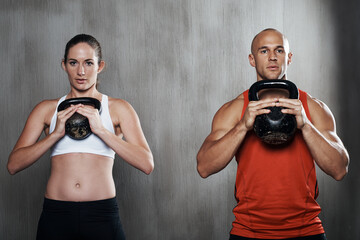 Sticker - They're committed to staying in shape. A man and woman working out with kettle bells at the gym.