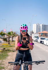 Wall Mural - female biker staring at cellphone and smiling on the bikeway in the city