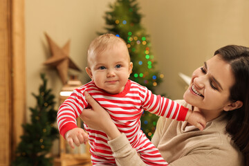 Wall Mural - Happy you mother with her cute baby in room decorated for Christmas. Winter holiday