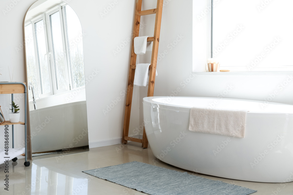 Stylish interior of modern light bathroom with big mirror