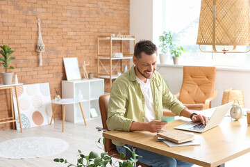 Wall Mural - Handsome man working with laptop at table in office