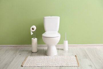 Wall Mural - Holder with rolls of paper, toilet bowl and brush near green wall