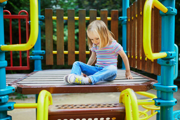 Girl on playground on a sunny day. Preschooler child playing on a slide. Outdoor activities for kids