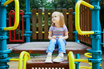 Wall Mural - Girl on playground on a sunny day. Preschooler child playing on a slide. Outdoor activities for kids