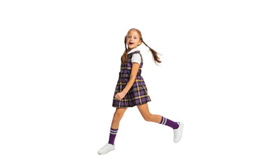 Portrait of cute little girl, pupil in school uniform running isolated on white background. Concept of childhood, emotions, study