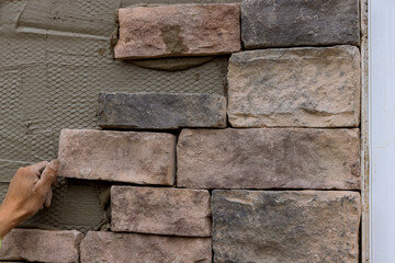 The process of laying decorative stone bricks on the wall.