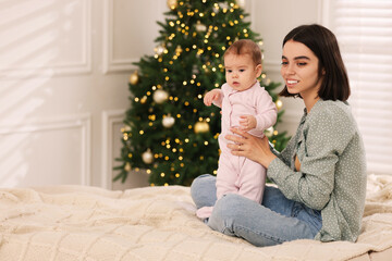 Canvas Print - Happy young mother with her cute baby on bed at home, space for text. Winter holiday