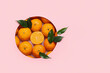 Composition with ripe tangerines and leaves on pink background