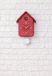 Red cuckoo clock on white brick wall	