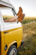 legs peeping out of van's window. alternative way of travel and enjoy the world. discover new places and live with nature view. cropped young caucasian female have rest in classic van, relax