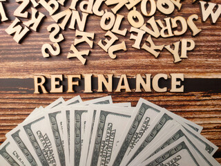 Top view wooden word and banknotes with text REFINANCE on a wooden background.