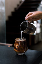 Barista Pouring Milk Into A Glass Of Iced Coffee