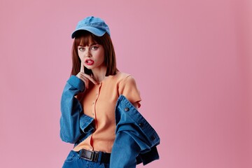 Wall Mural - Positive young woman in a cap and denim jacket posing pink background unaltered