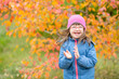 © Ermolaev Alexandr - Joyful girl with Downs syndrome throwing autumn leaves at autumn park. Empty space for text