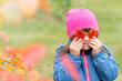 © Ermolaev Alexandr - Young girl with Downs syndrom holds autumn leaves lika eyeglasses. Empty space for text