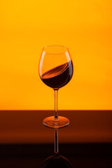 Wall Mural - glass goblet of red wine on an orange background