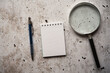 notes, lupa i długopis na betonowym stole