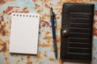 notes ,długopis i czarny portfel na drewnianym  stole