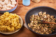 Ingredients for cooking pasta with mushroom sauce and pancetta - fried mushrooms in a frying pan and raw fettuccine in a plate