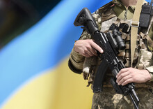 Soldier With Assault Rifle And Flag Of Ukraine. Ukrainian Soldier With Assault Rifle AK.