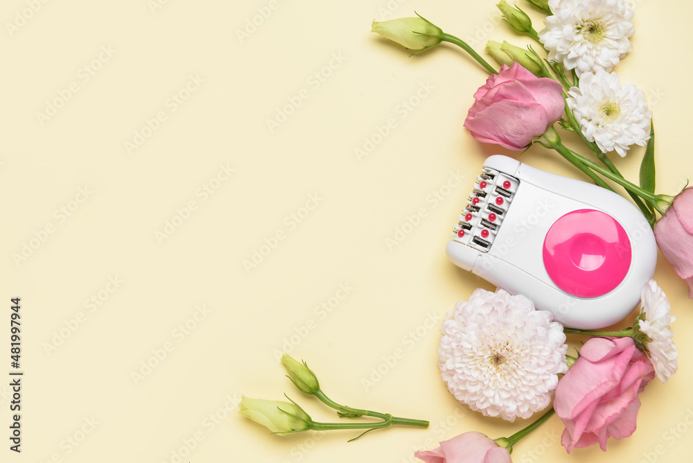 Modern epilator and beautiful flowers on yellow background