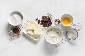 Wall Mural - Bowl with butter and ingredients for preparing chocolate brownie on white background