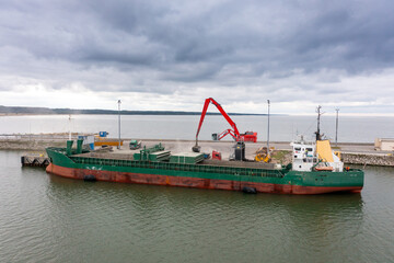 An aerial drone view of the industrial port in the Baltic Sea. There is a ships under load in the harbor.	