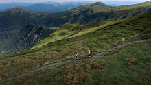 Two Hikers With Backpacks Are Walking Along Mountain Range In Carpathian Mountains
