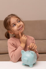 Wall Mural - Cute little girl with piggy bank at home. Adorable child with moneybox. Lifestyle and real people concept. Children's pocket money. Savings, budget planning starts from childhood.