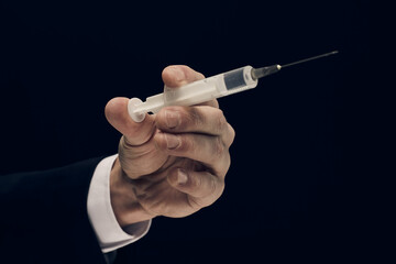 Wall Mural - Injection syringe in human hand on black background