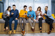 © maxbelchenko - Group of young people using mobile phone. Business colegios sitting side by side in a modern office using digital devices. Study, business, technologies.