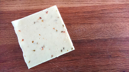 Pepper jack cheese - 1 slice on a wooden cutting board