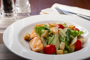 Wall Mural - Caesar salad with salmon and parmesan on white plate