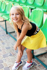 cute little girl during break between sport training on the stadium sitting on a bench