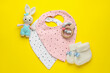 Flat lay composition with drool baby bibs and accessories on yellow background